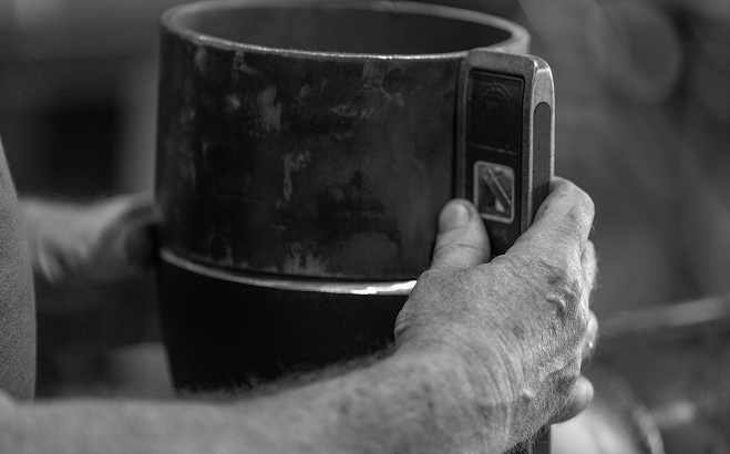 Close-up of hands holding tool against metal cylinder