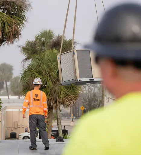 Mid-State technicians in hard hats positioning a rooftop HVAC unit