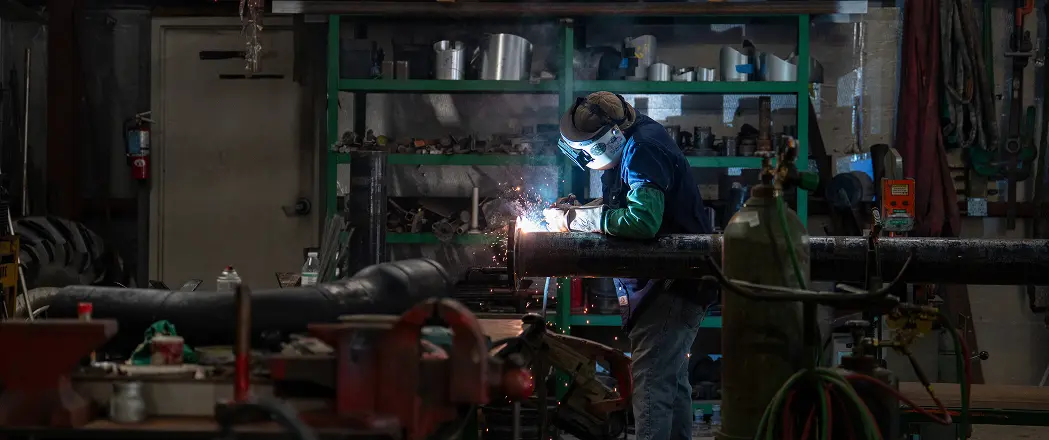 Technician welding pipe in the Mid-State fabrication shop