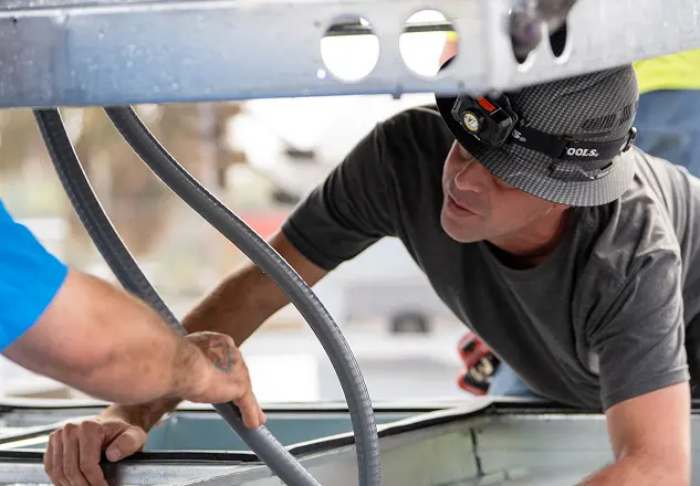 Technician in a hard hat servicing mechanical equipment